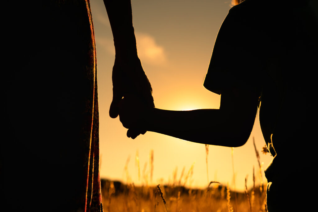 silhouette of a parent holding a child's hand